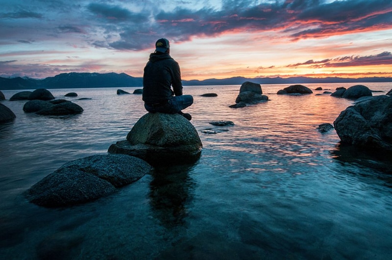 man siting on a rock meditating